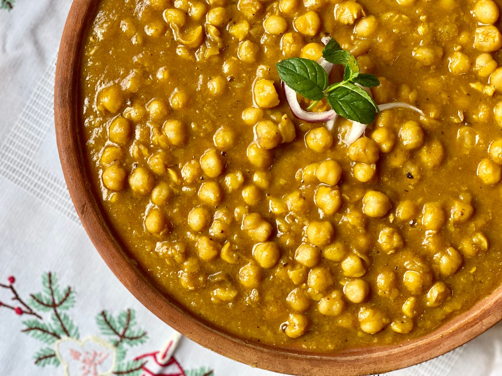 Close-up of chana masala showing whole chickpeas and some crushed into the thickened gravy